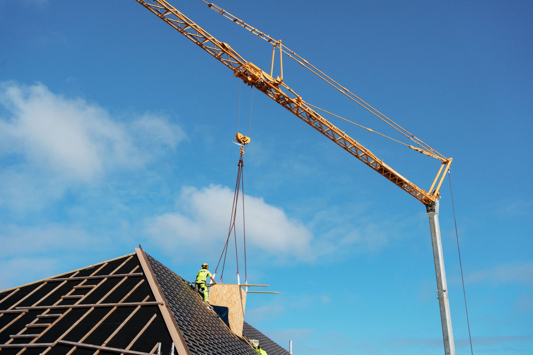 Crane lifting a chimney element onto a roof under construction