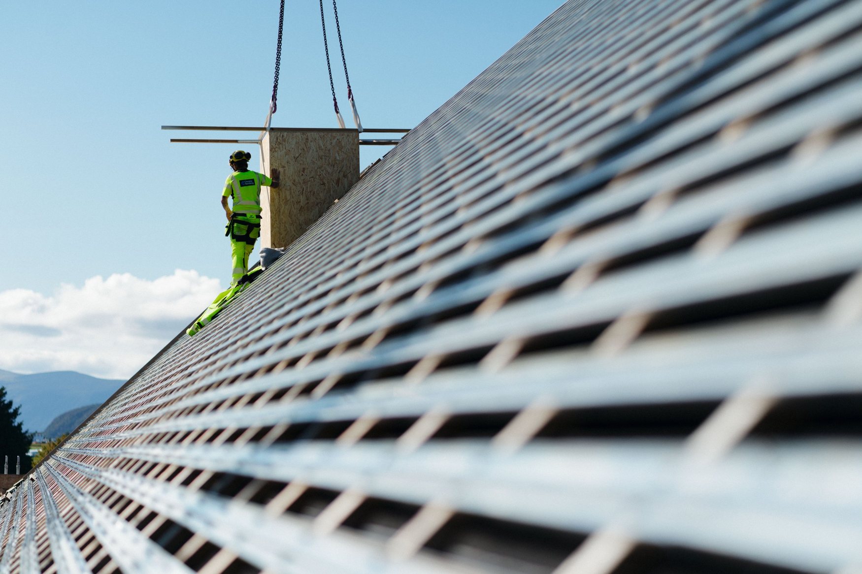 Christie Nordang worker guiding a crane lift on a roof