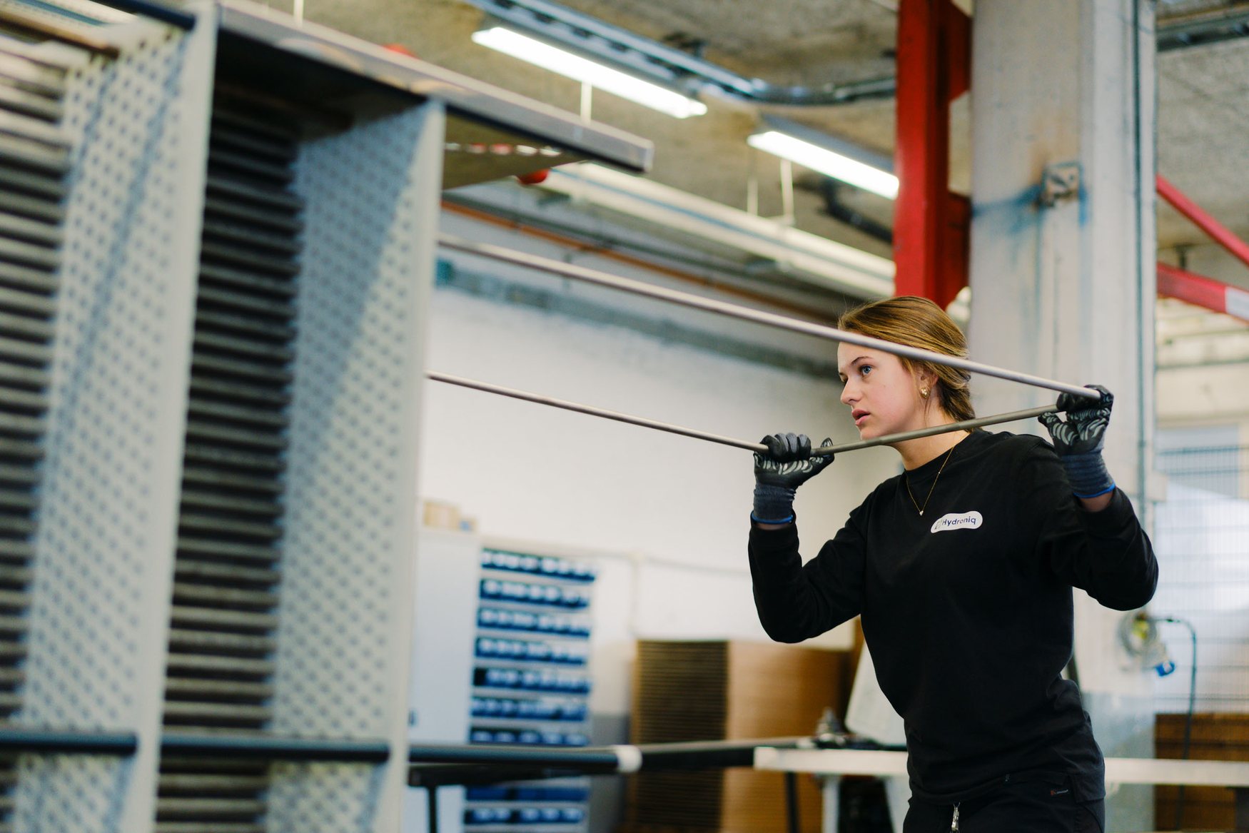Hydroniq employee handling steel tubes in the production hall