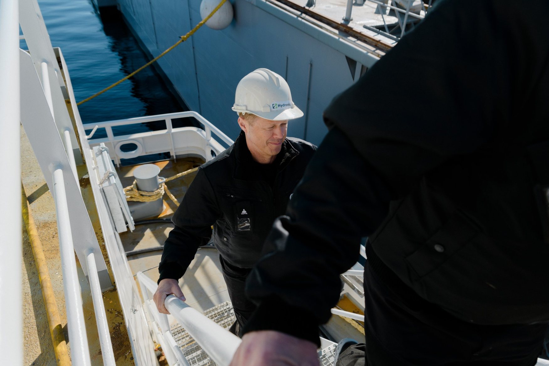 Hydroniq employee in a hard hat climbing the gangway onto a vessel