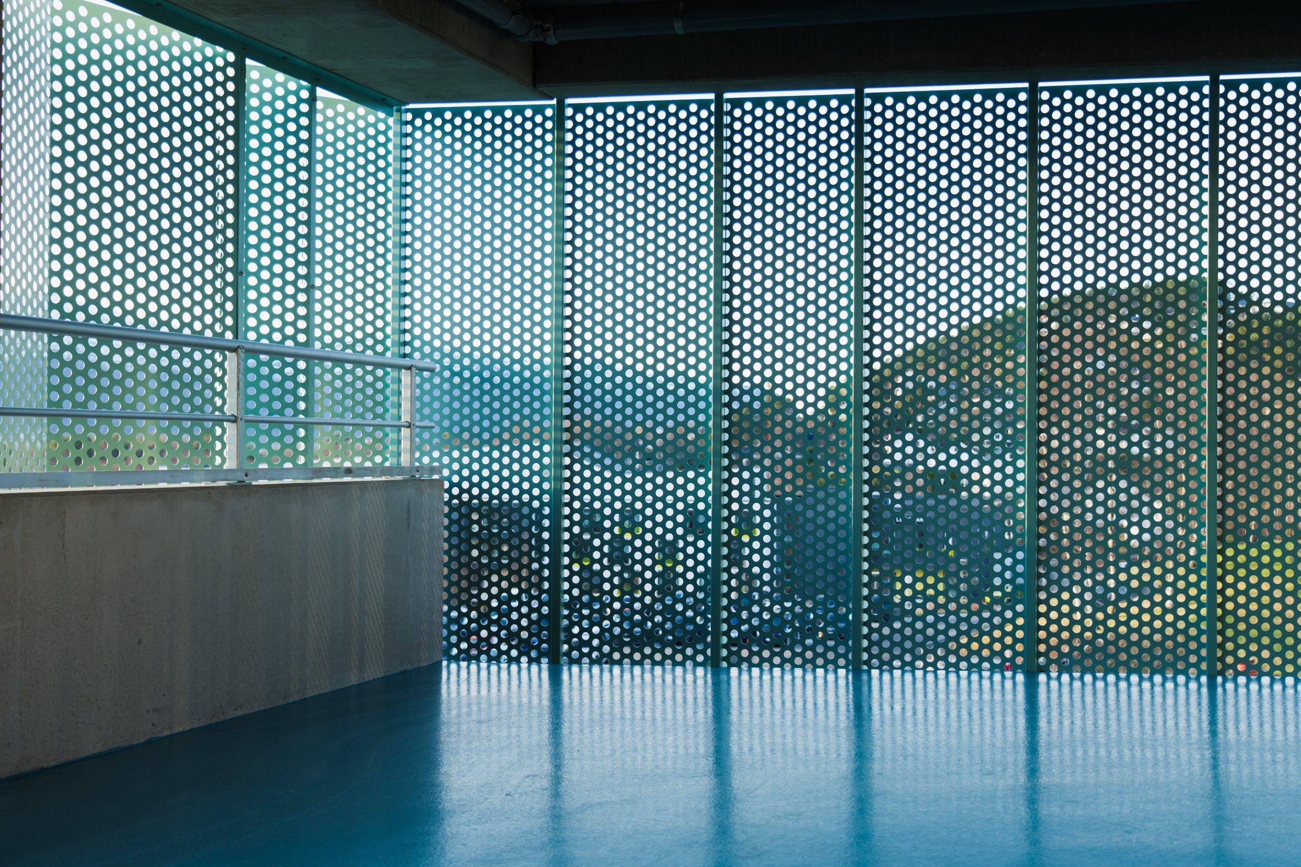 Perforated teal facade panels and blue floor in the parking garage