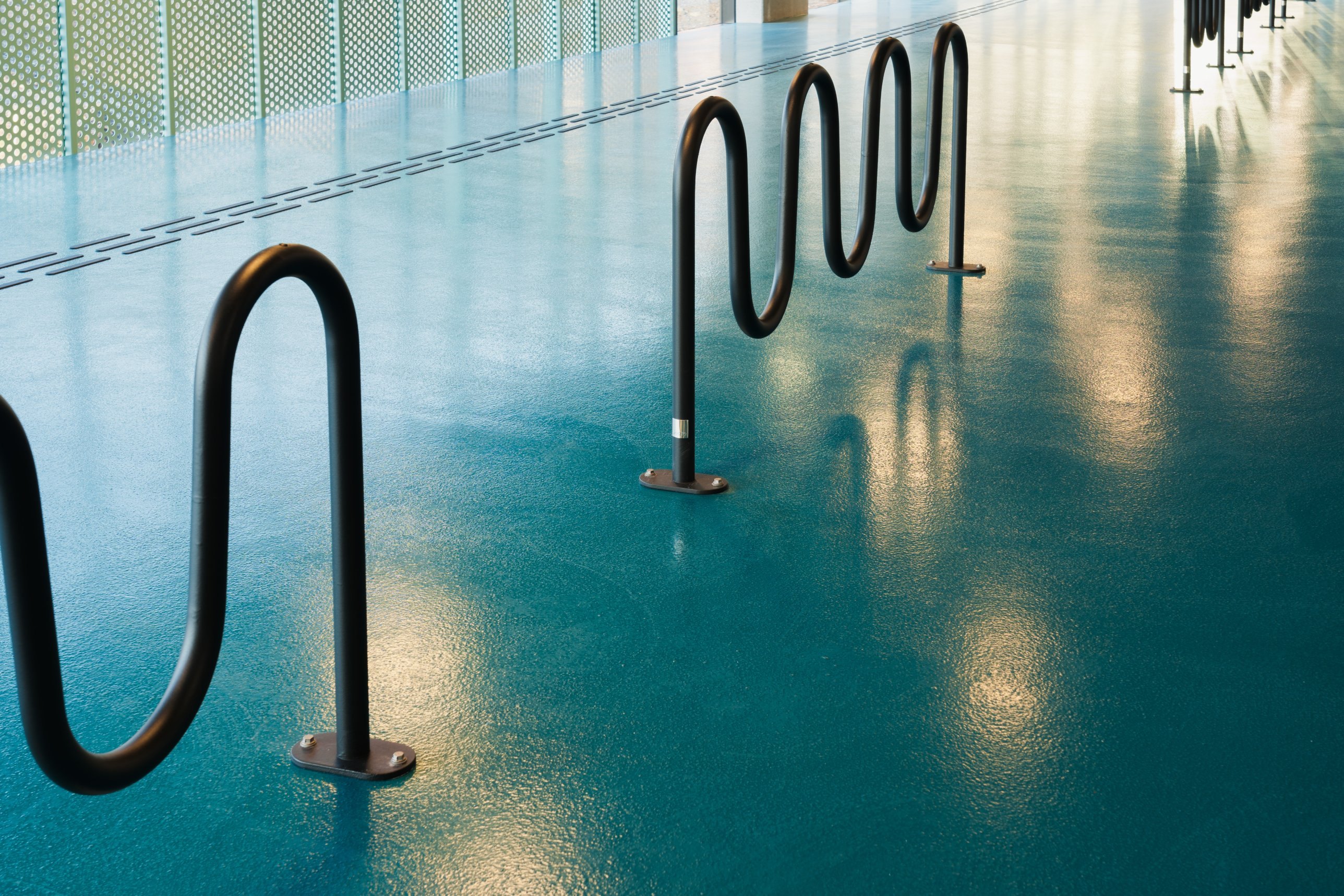Wave-shaped bicycle racks on a blue floor