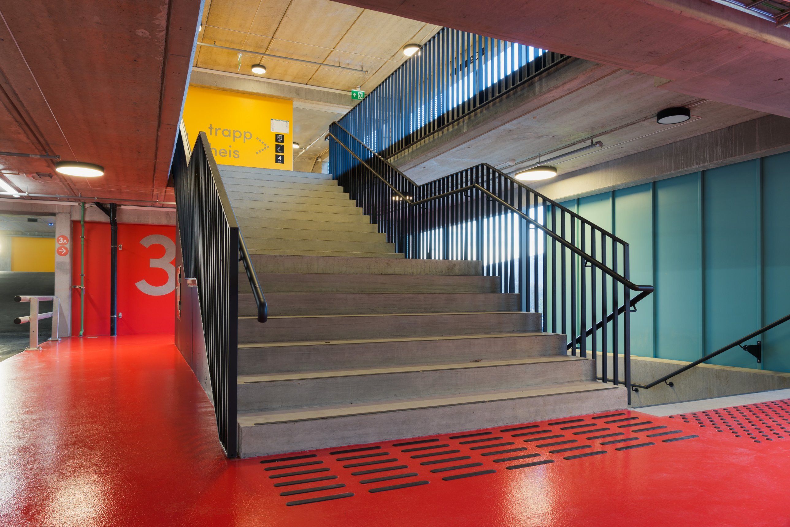 Red-floored stairwell with concrete stairs and yellow signage
