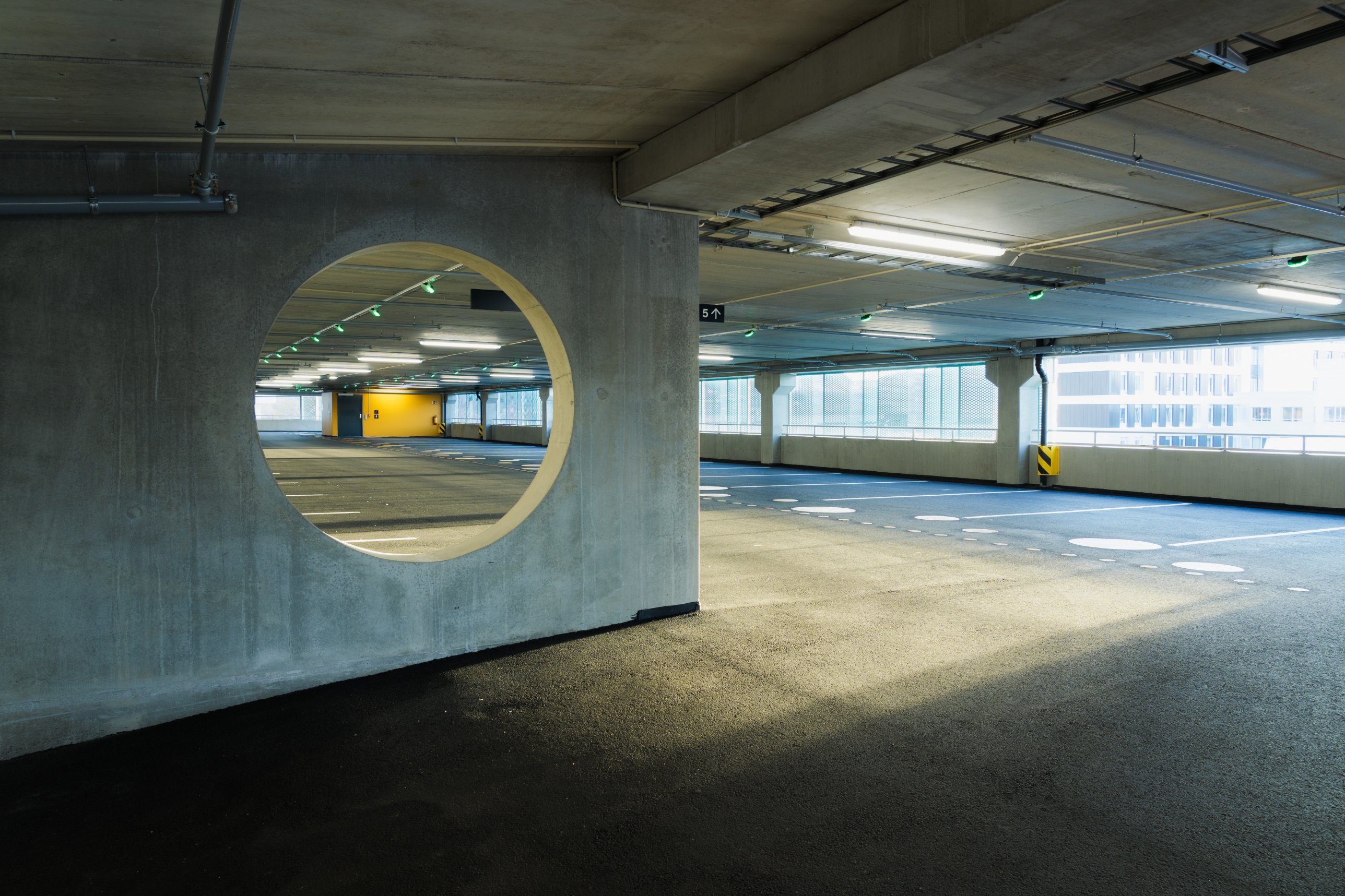 Concrete wall with circular opening on an empty parking deck