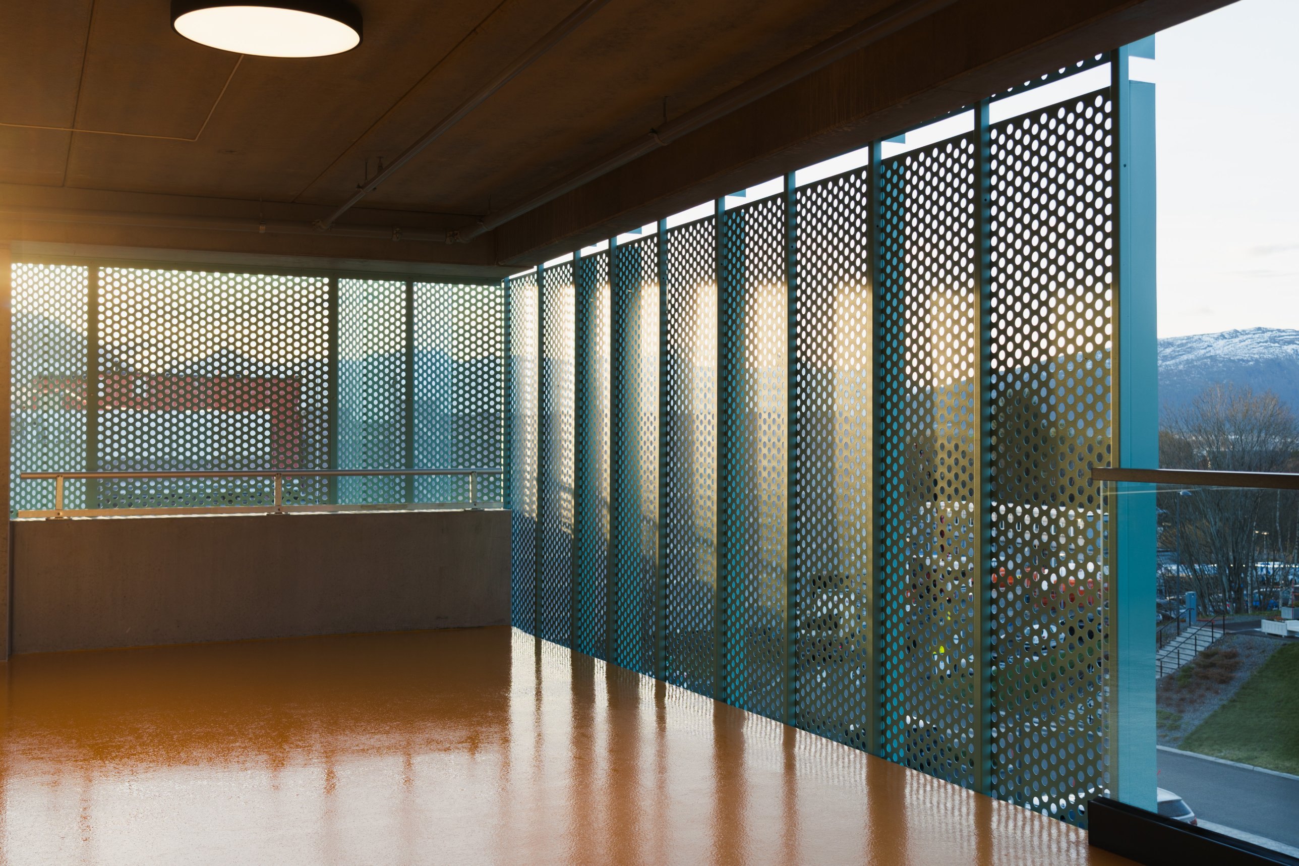 Low sun through perforated panels onto an orange floor