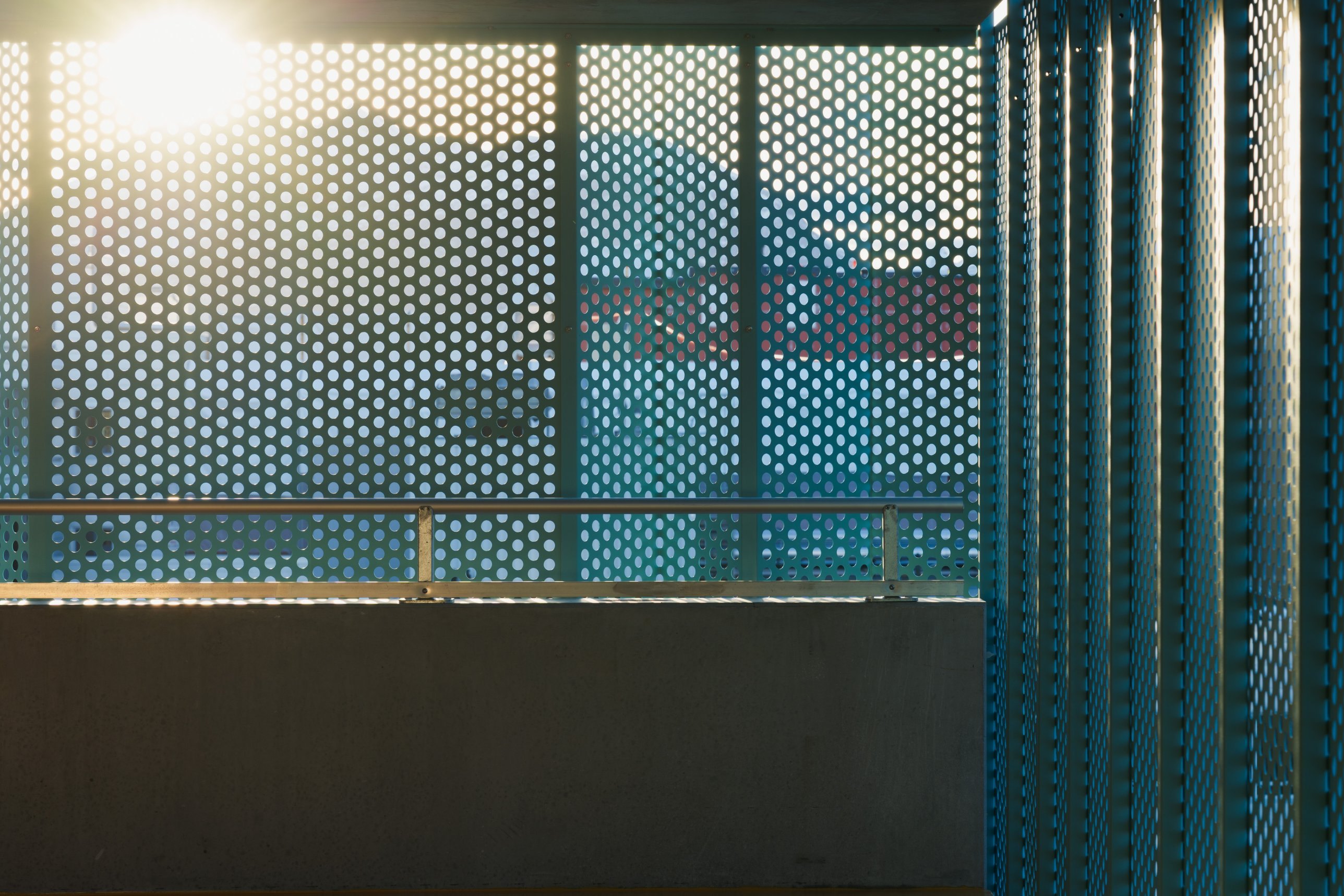 Backlit perforated facade panels above a concrete parapet
