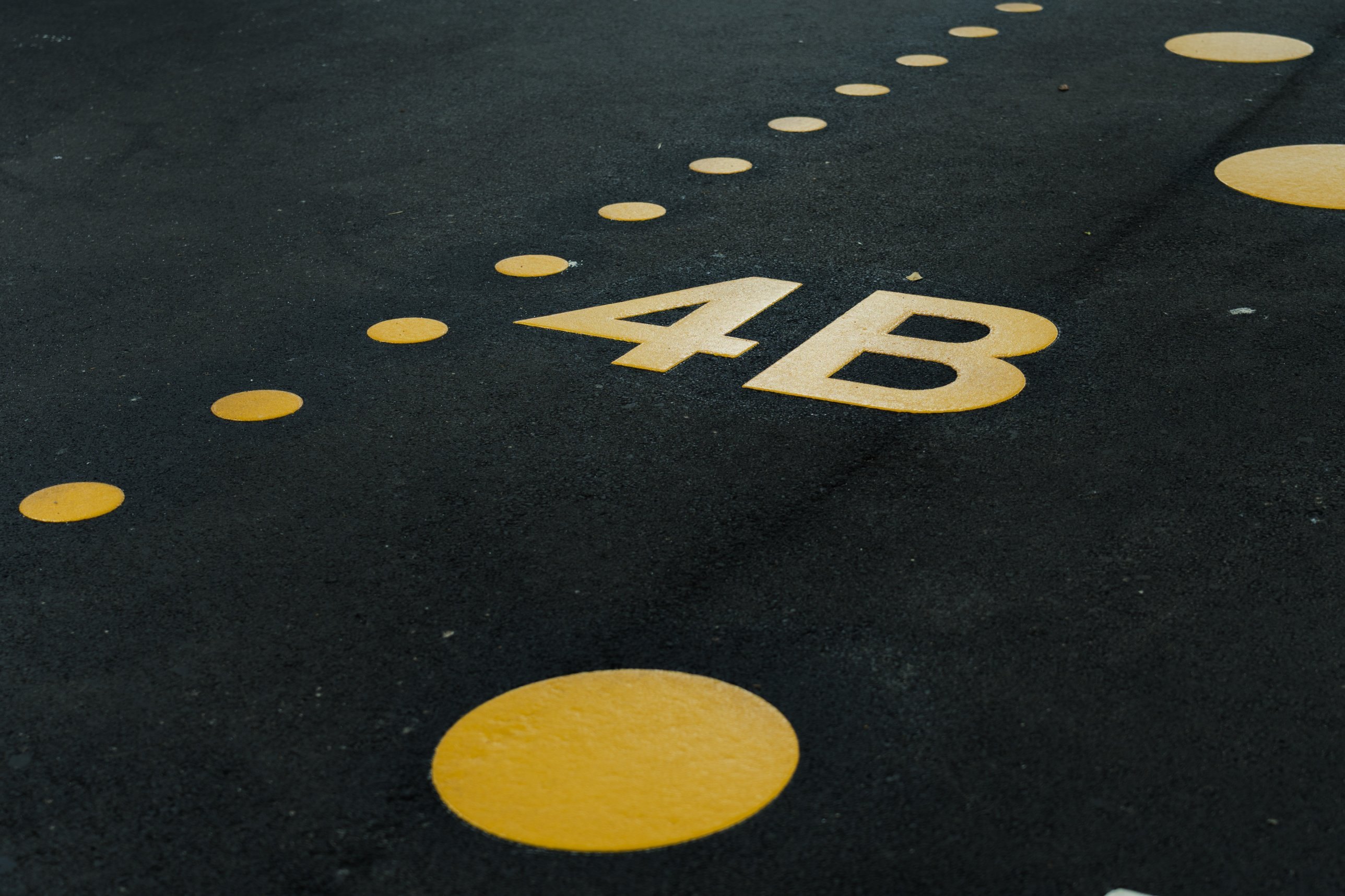 Yellow 4B floor marking and dots on dark asphalt