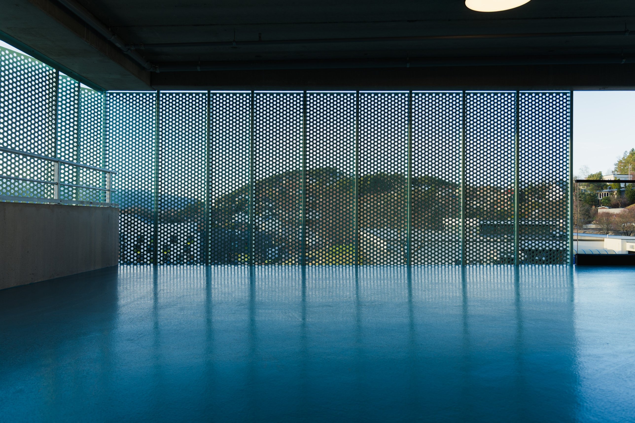 Perforated facade panels reflected in a blue floor